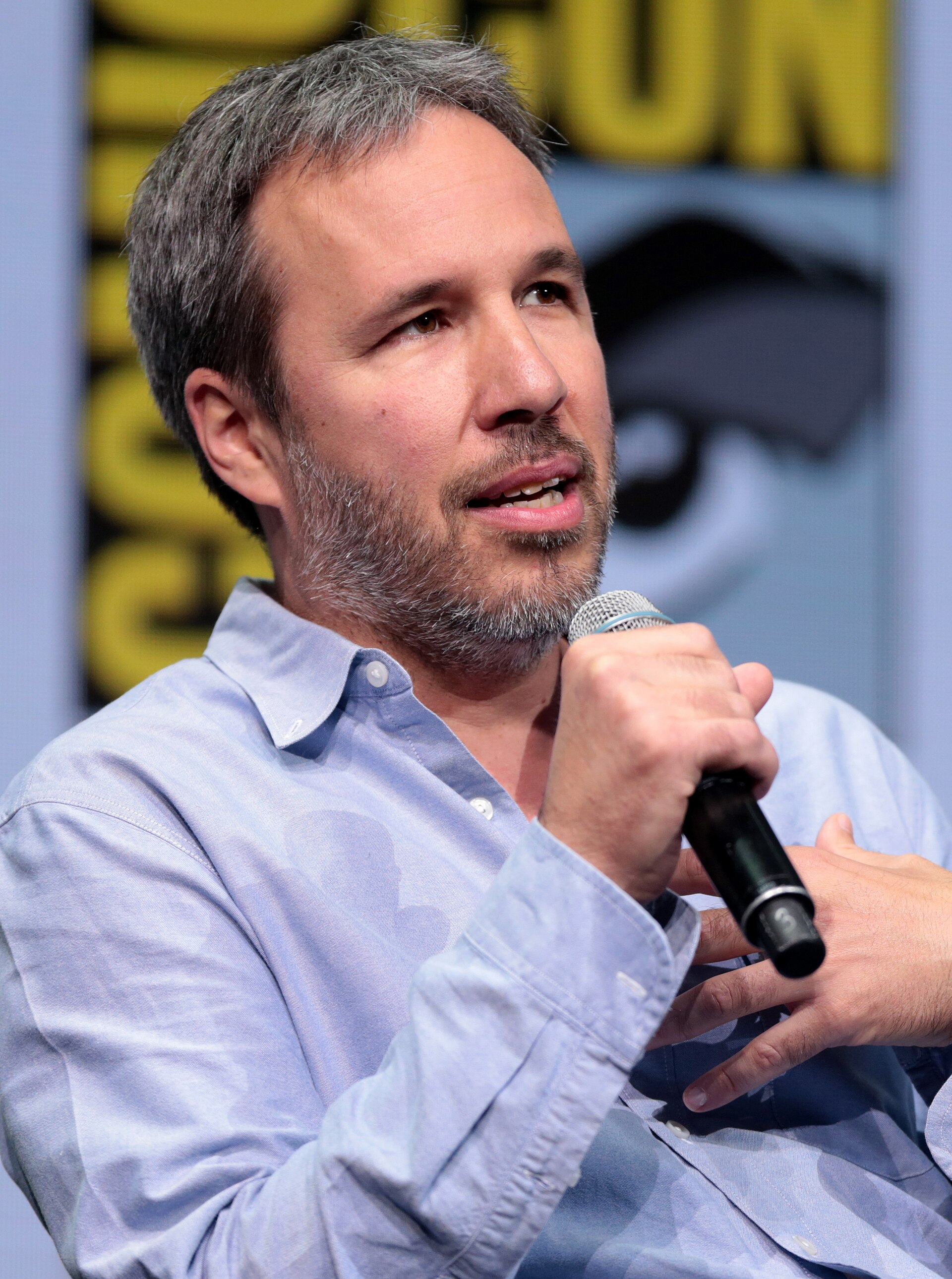 Director Denis Villeneuve on set, framed against a desert landscape evoking his Dune adaptations